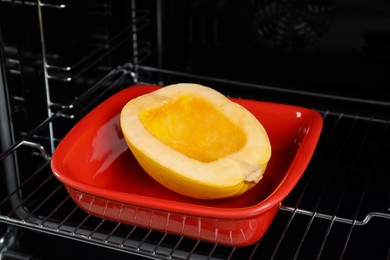 Photo of Baking dish with half of fresh spaghetti squash in oven