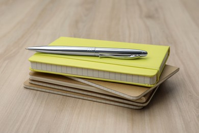 Stack of planners and pen on wooden table