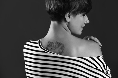 Young woman with tattoo on dark background. Black and white photography