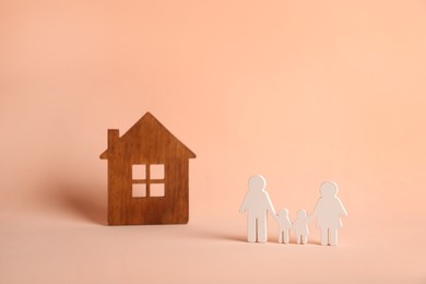 Figures of family and house on pink background. Space for text