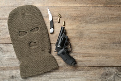 Photo of Flat lay composition with balaclava and weapons on wooden table, space for text