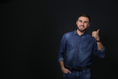 Photo of Man showing THUMB UP gesture in sign language on black background