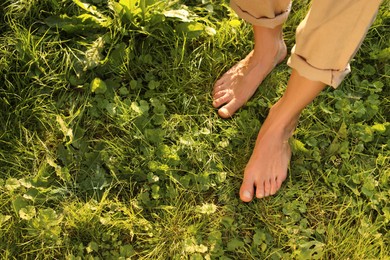 Woman walking barefoot on green grass outdoors, above view. Space for text