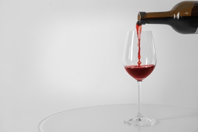 Pouring red wine into glass on white background