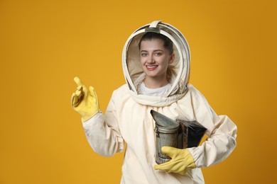 Photo of Beekeeper in uniform with smokepot pointing at something on yellow background