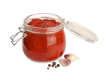 Glass jar of delicious canned lecho, garlic and peppercorns on white background