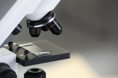 Photo of Modern medical microscope with glass slide on blurred background, closeup. Space for text