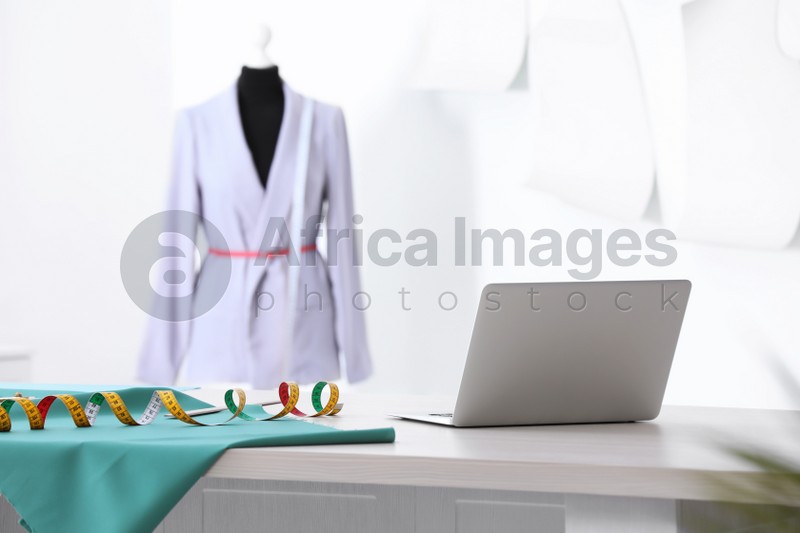 Photo of Table with laptop, cloth and measuring tape in tailor studio