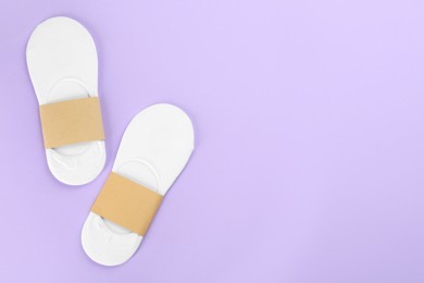 Soft cotton socks on lilac background, flat lay. Space for text