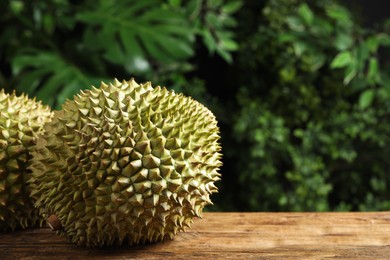 Ripe durians on wooden table against blurred background. Space for text