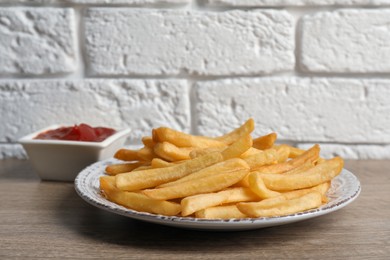 Photo of Tasty french fries served with ketchup on wooden table