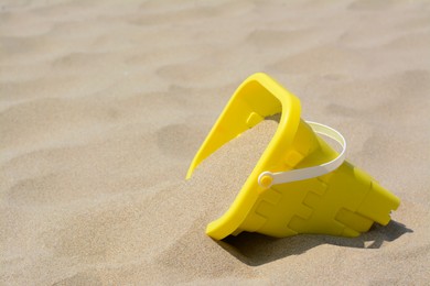 Yellow plastic bucket on sand, space for text. Beach toy