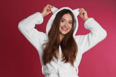 Young woman in bathrobe with funny hood on crimson background