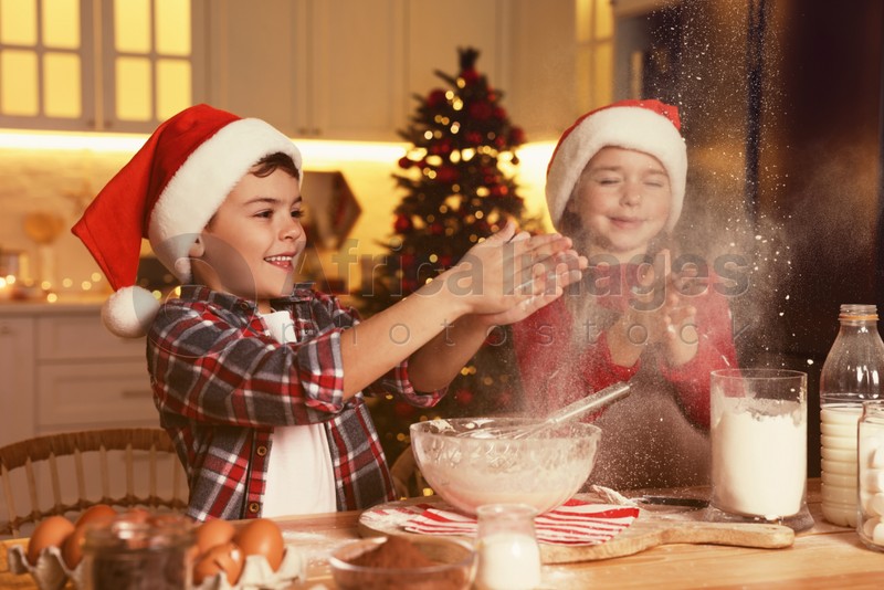 Photo of Happy little children having fun while making dough for Christmas cookies at home