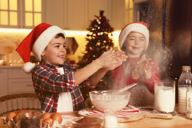 Happy little children having fun while making dough for Christmas cookies at home