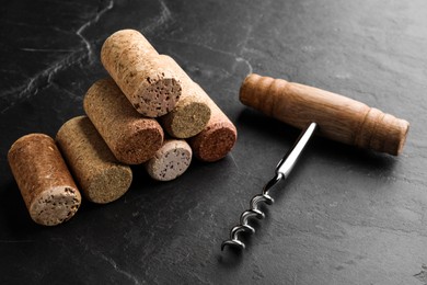 Corkscrew and stack of wine bottle stoppers on slate table, closeup