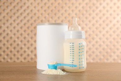 Blank can of powdered infant formula with feeding bottle and scoop on wooden table. Baby milk
