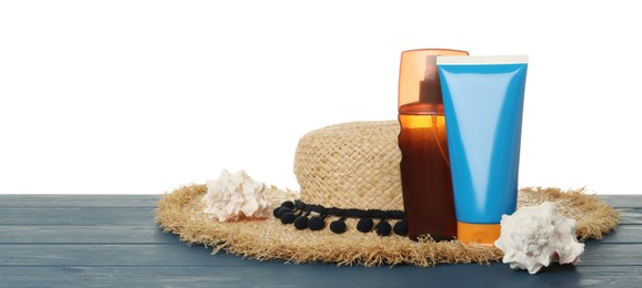 Sun protection products, shells and beach hat on blue wooden table