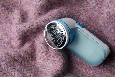Photo of Modern fabric shaver on pink woolen sweater