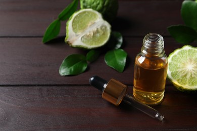 Bottle of essential oil, pipette and fresh bergamot fruit on wooden table. Space for text