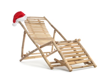 Wooden deck chair and Santa Claus hat on white background. Christmas vacation