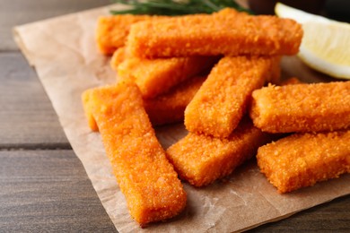 Fresh breaded fish fingers served on wooden table, closeup