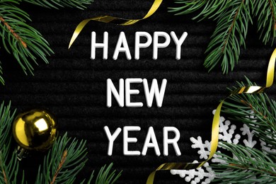 Happy New Year greeting card. Phrase made with letters and decor on black background, flat lay