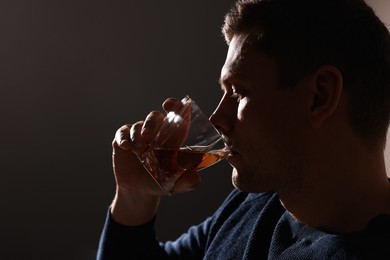 Addicted man drinking alcohol on dark background, closeup