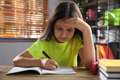 Photo of Emotional preteen girl doing homework at table