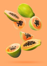 Image of Cut and whole papaya fruits falling on pale orange background
