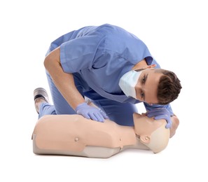 Doctor in uniform and protective mask practicing first aid on mannequin against white background