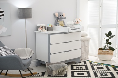Beautiful baby room interior with modern changing table and rocking chair