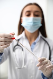 Doctor holding buccal cotton swab and tube for DNA test in clinic, focus on hands