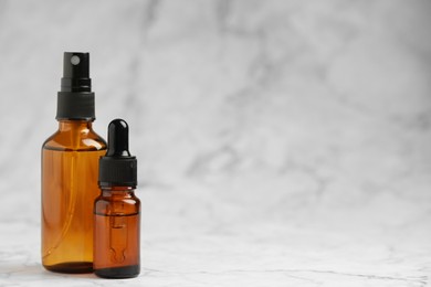 Photo of Bottles of organic cosmetic products on grey marbled background, space for text
