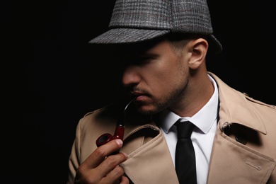 Old fashioned detective with smoking pipe on dark background, closeup
