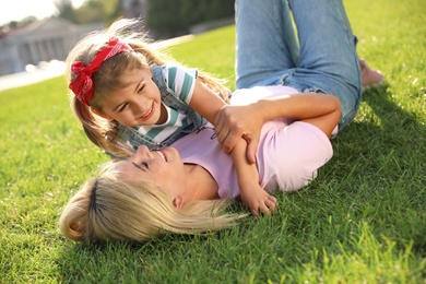 Happy mother and her child having fun on green grass. Spending time in nature