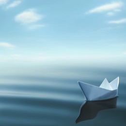 Image of White paper boat floating on calm sea. Space for text