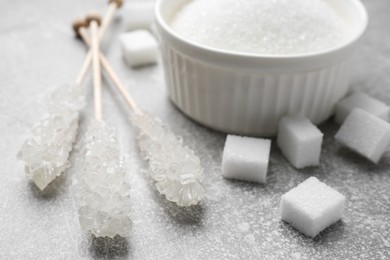Different types of sugar on light grey table, closeup