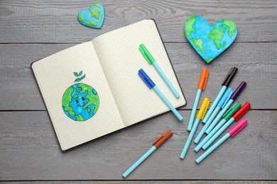 Happy Earth Day. Flat lay composition with notebook and markers on grey wooden table