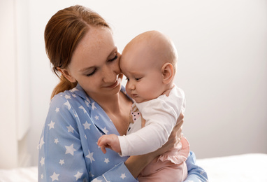 Young woman with her little baby resting after breast feeding on bed