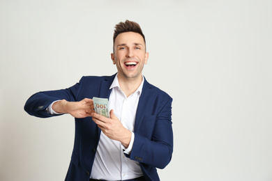 Happy man throwing money on light grey background. Space for text