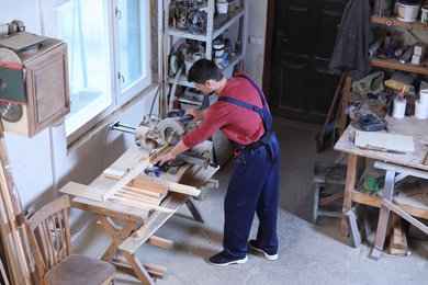 Mature working man using circular saw at carpentry shop, above view
