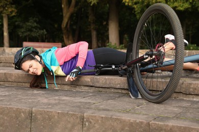 Young woman fallen off her bicycle on steps outdoors