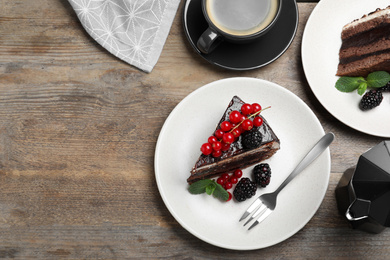 Tasty chocolate cake with berries on wooden table, flat lay