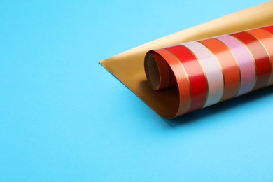 Roll of striped paper on light blue background, closeup. Space for text