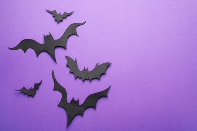 Paper bats and space for text on purple background, flat lay. Halloween decor