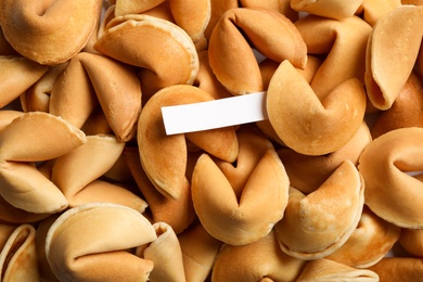 Paper with prediction on pile of fortune cookies, top view