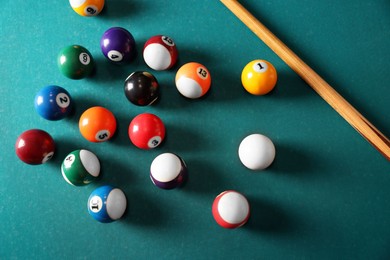 Photo of Many colorful billiard balls and cue on green table, above view