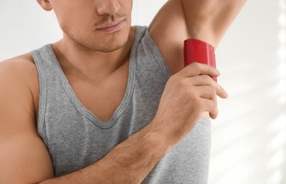Photo of Man applying deodorant to armpit at home, closeup