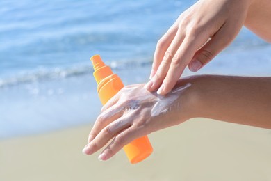 Woman applying sun protection cream on her hand at beach, closeup